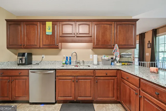 a kitchen with granite countertop wooden cabinets a sink and dishwasher
