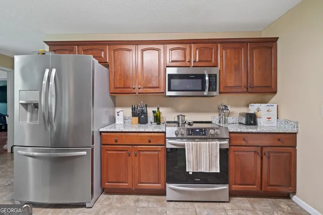a kitchen with stainless steel appliances granite countertop a refrigerator stove and microwave