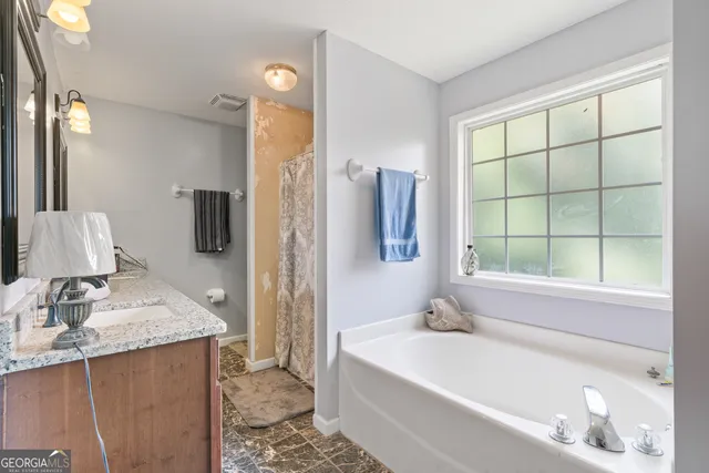a bathroom with a granite countertop sink and a bathtub