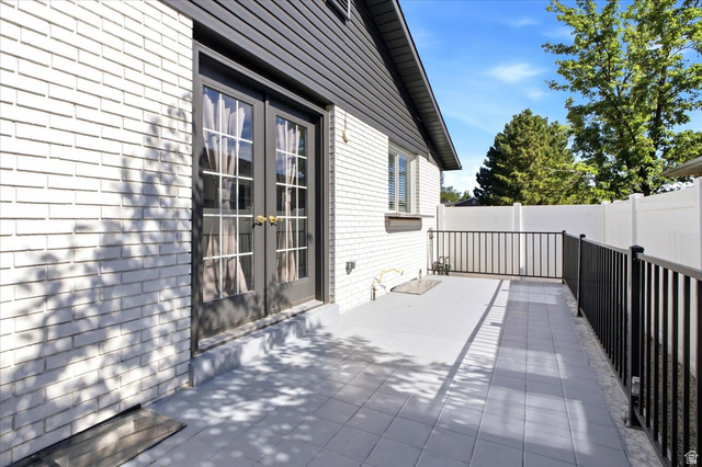 1676 East 11245 South Sandy, UT 84092 - Photo 31 of 34 Patio featuring a durable tiled surface, black metal railing, white brick exterior, and French doors