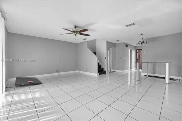 a view of an empty room and a chandelier fan