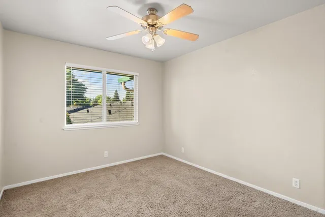 an empty room with a window and a fan