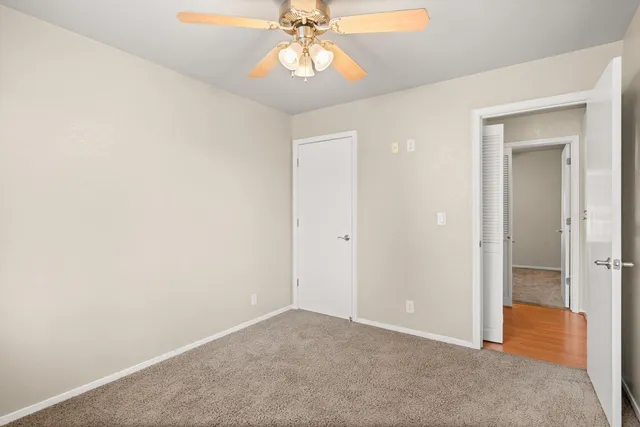 an empty room with a chandelier fan and windows