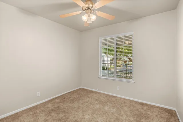 an empty room with a window and a fan