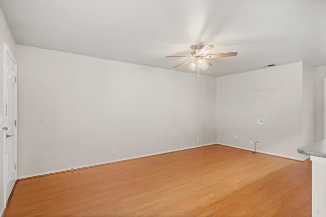 an empty room with a window and a ceiling fan