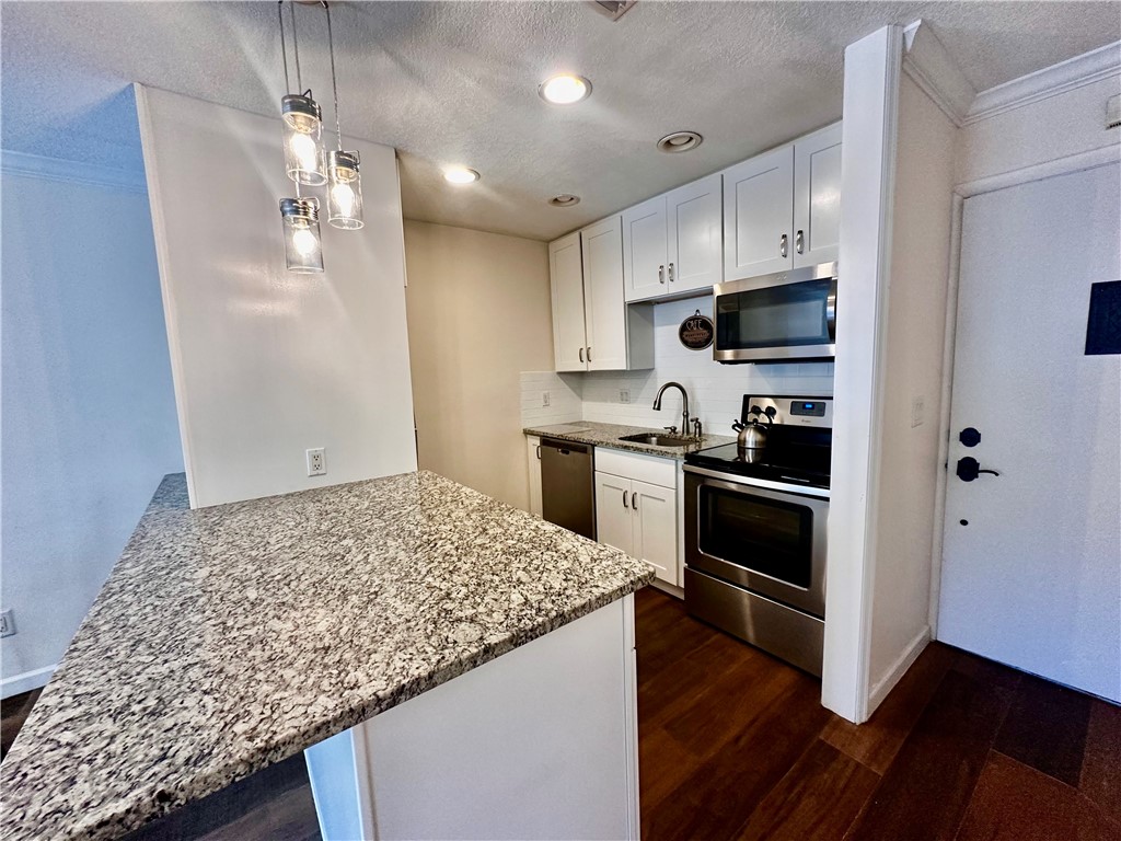 1815 Robalo Drive, Unit C201 Vero Beach, FL 32960 - Photo 5 of 31 a kitchen with kitchen island white cabinets appliances and wooden floor