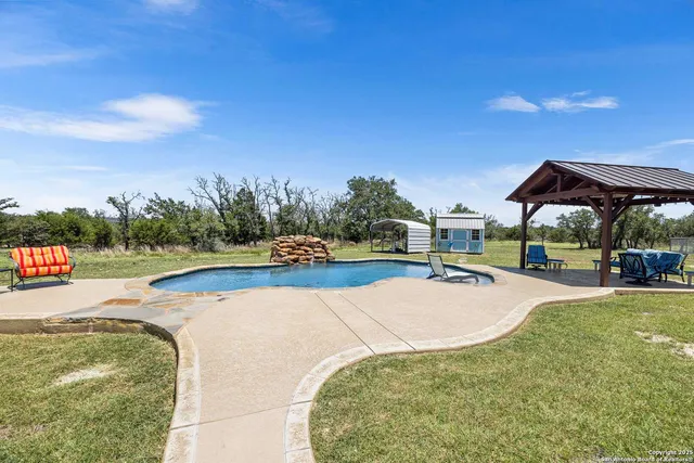 a view of swimming pool with a table and chairs under an umbrella