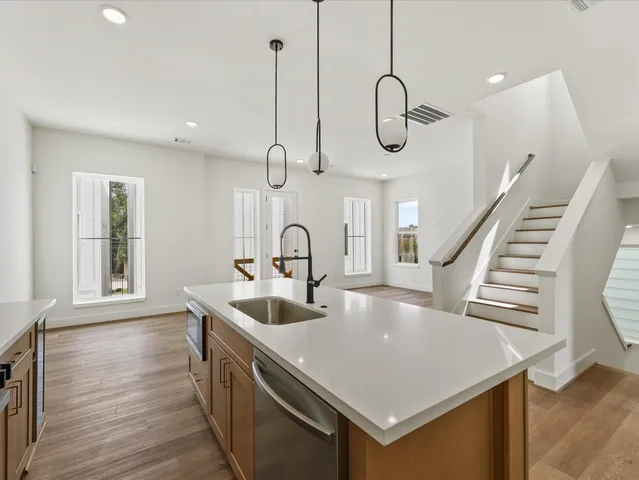 a kitchen with kitchen island granite countertop a sink a counter space appliances and cabinets