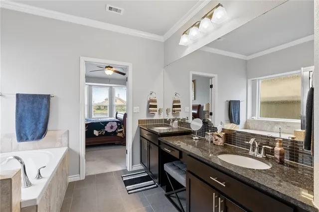 a en suite bathroom with a granite countertop double vanity sink and a mirror