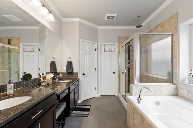 a bathroom with double vanity sinks a granite tub shower and a mirror