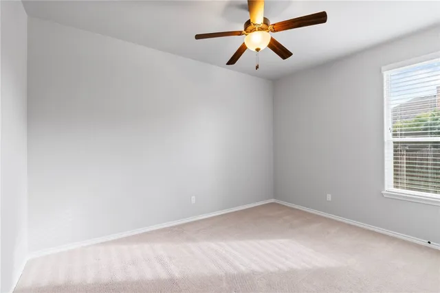 an empty room with a window and a fan