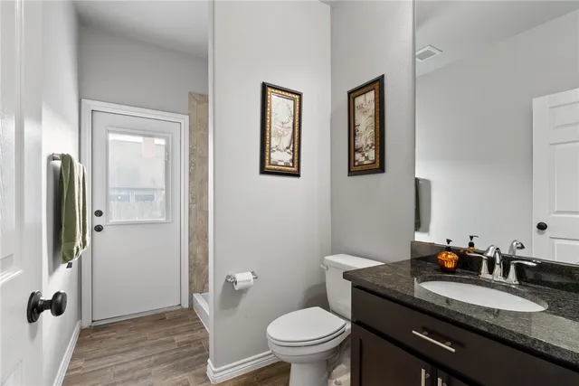a bathroom with a granite countertop toilet a sink and mirror