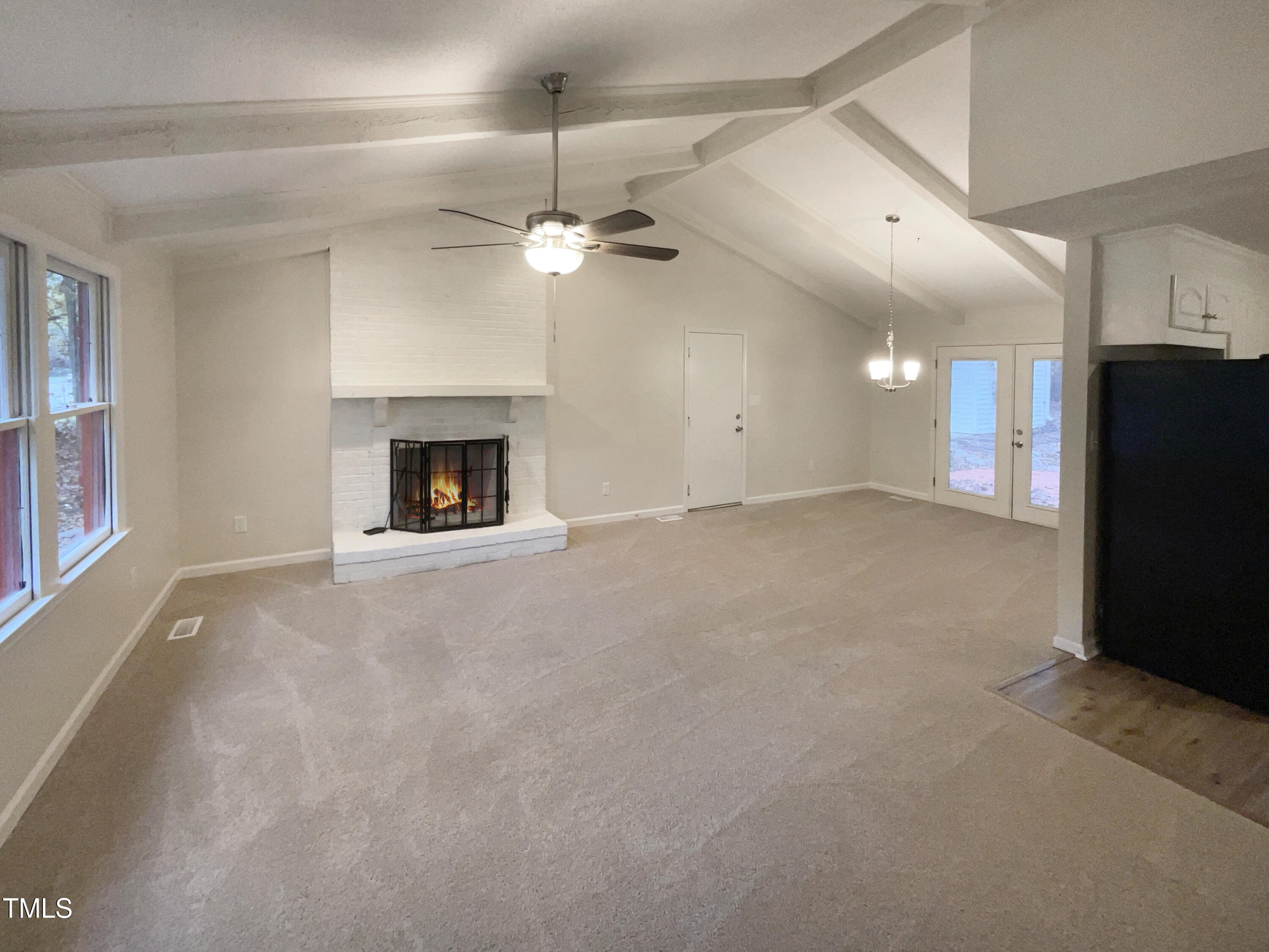 6605 Glendower Road Raleigh, NC 27613 - Photo 3 of 23 an empty room with windows fireplace and a ceiling fan