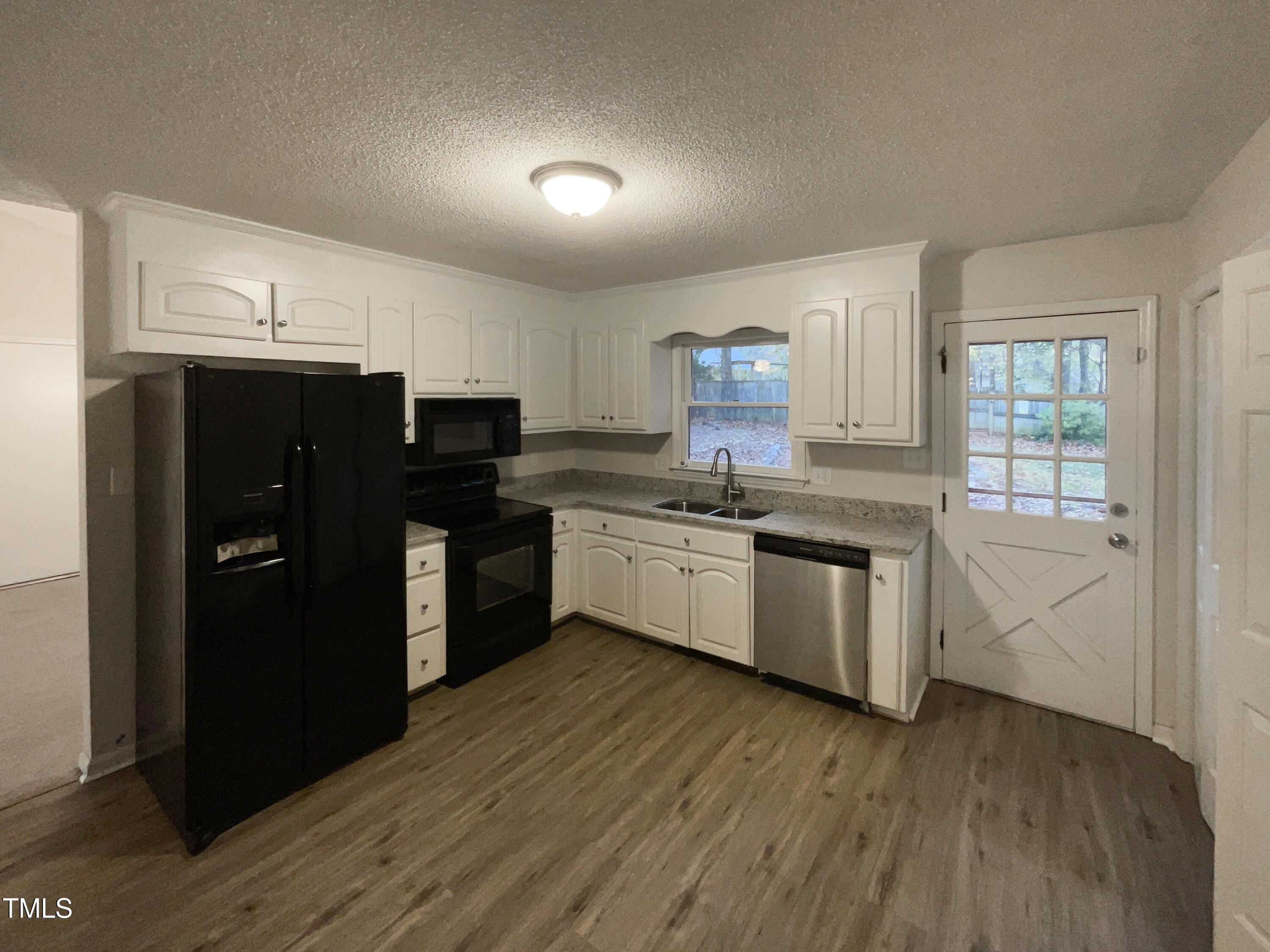 6605 Glendower Road Raleigh, NC 27613 - Photo 6 of 23 a kitchen with a sink a refrigerator and cabinets