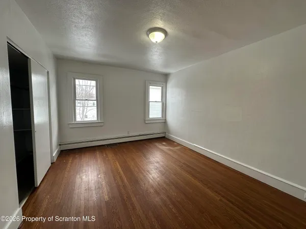 an empty room with wooden floor and windows