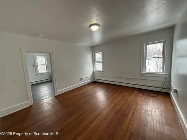 an empty room with wooden floor and windows
