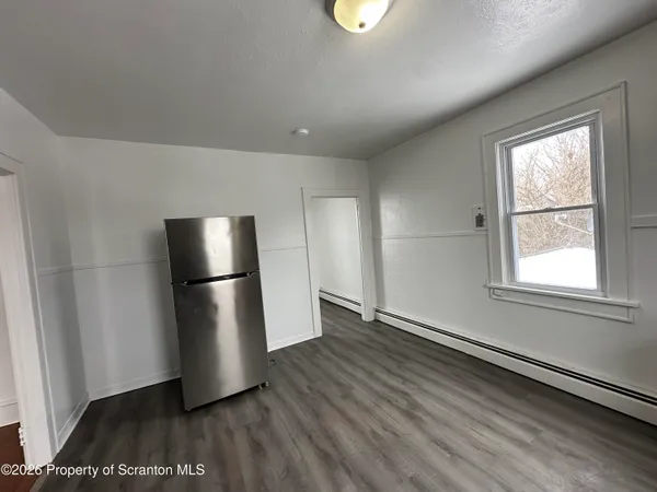 a view of empty room with wooden floor and window