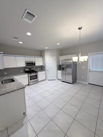 a kitchen with granite countertop a sink cabinets and stainless steel appliances