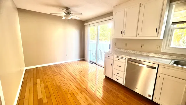 a kitchen with white cabinets and wooden floor