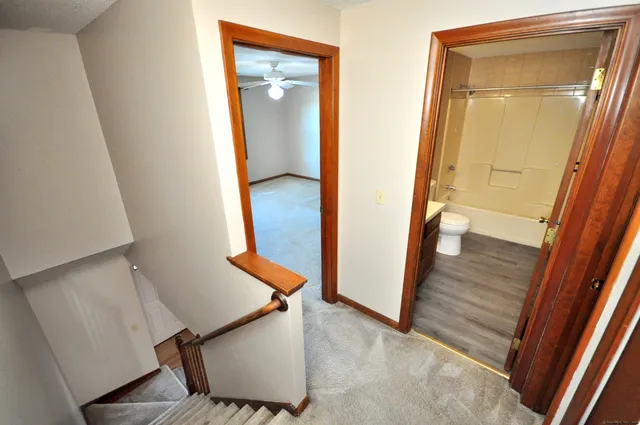 an empty room with chandelier fan and windows