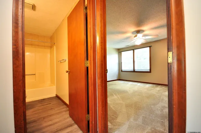 an empty room with chandelier fan and windows