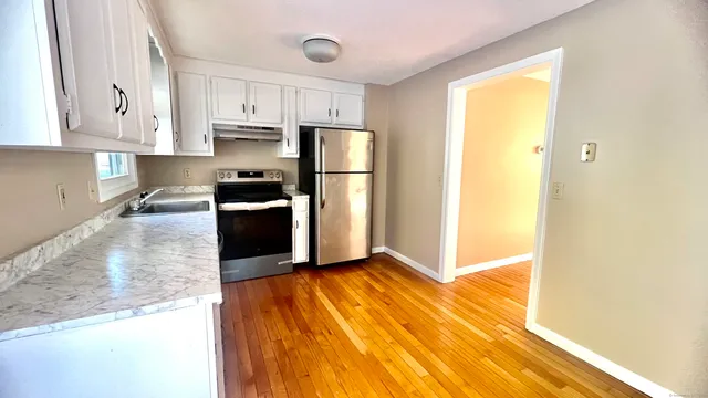 a kitchen with granite countertop white cabinets and stainless steel appliances