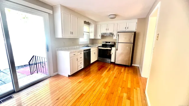 a kitchen with a refrigerator a sink and wooden floor