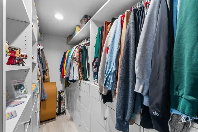 a view of walk in closet with clothes and shoes