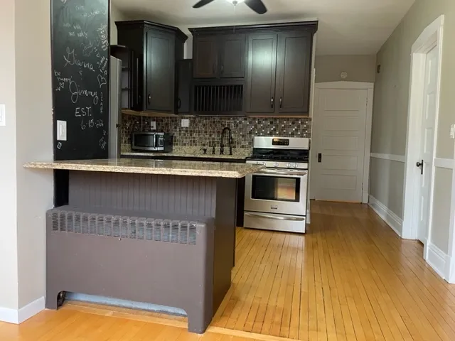 a kitchen with stainless steel appliances granite countertop a sink a stove and a wooden floors