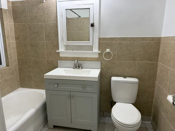 a bathroom with a toilet sink vanity tub and mirror