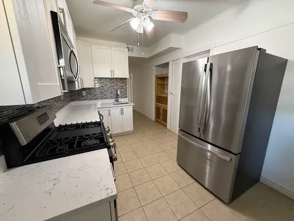 a kitchen with granite countertop a refrigerator and a stove top oven