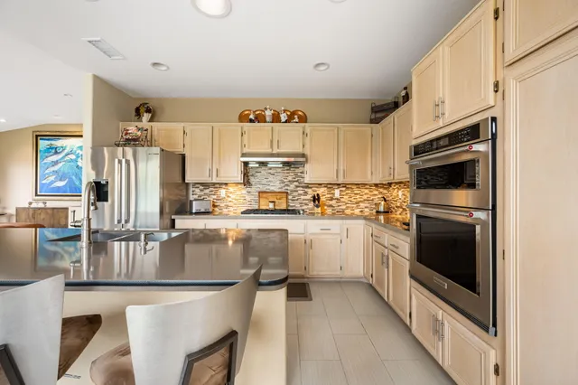 a kitchen with stainless steel appliances granite countertop a refrigerator a stove and a sink