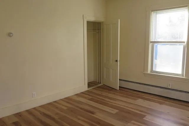 a view of an empty room with wooden floor and a window