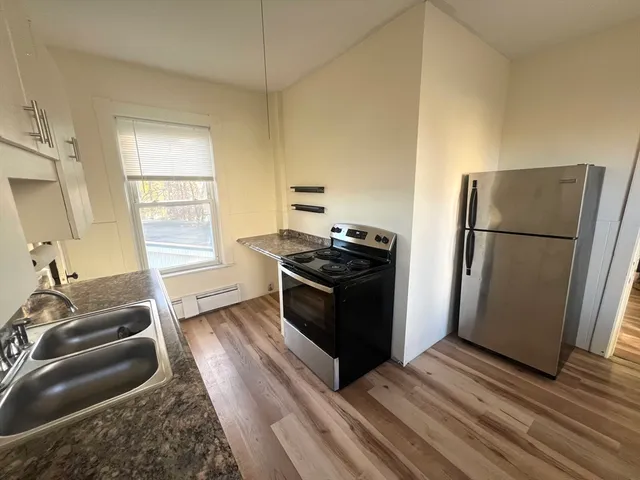 a kitchen with granite countertop a refrigerator and a stove top oven