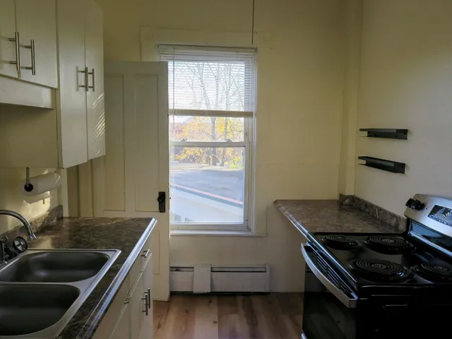 a kitchen that has a sink wooden floor and a stove