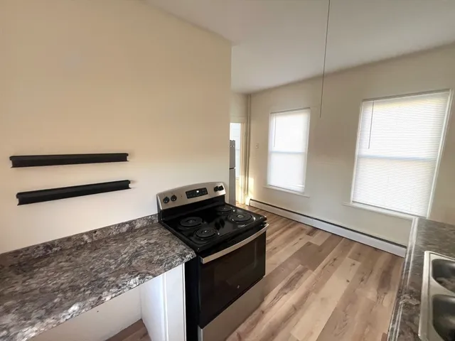 a kitchen with granite countertop stainless steel appliances a stove oven and white cabinets