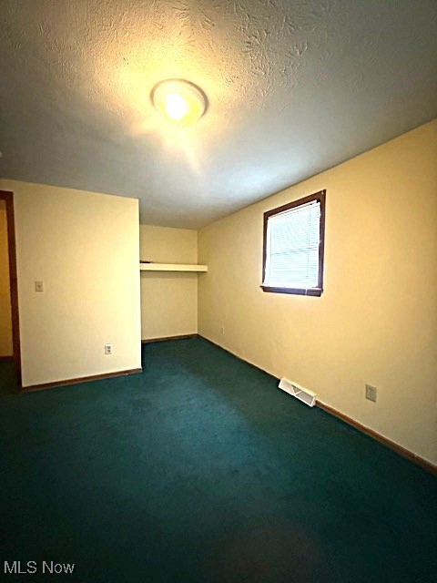 3804 Mahoning Road Northeast Canton, OH 44705 - Photo 11 of 22 Unfurnished room featuring baseboards, a textured ceiling, dark colored carpet, and visible vents