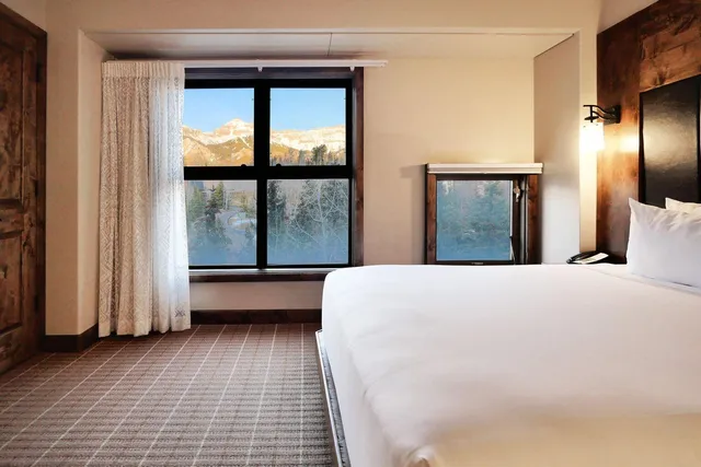 a large white bed in a room next to a window