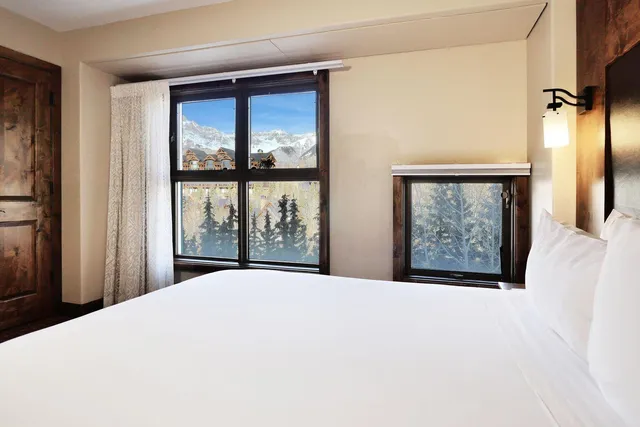 a bedroom with a large window and a wooden floor