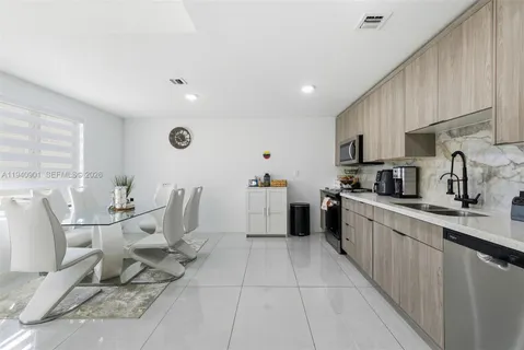 a large white kitchen with a large window and cabinets