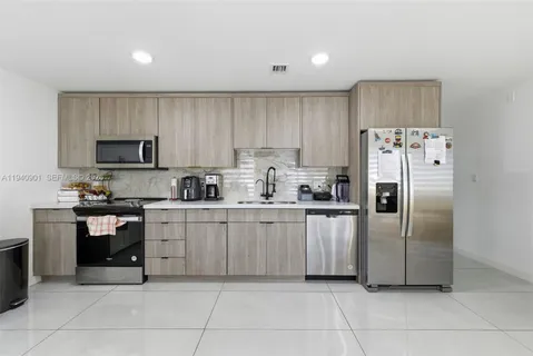 a kitchen with granite countertop a refrigerator and a stove top oven