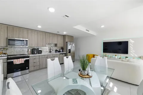 a living room with stainless steel appliances furniture and a flat screen tv