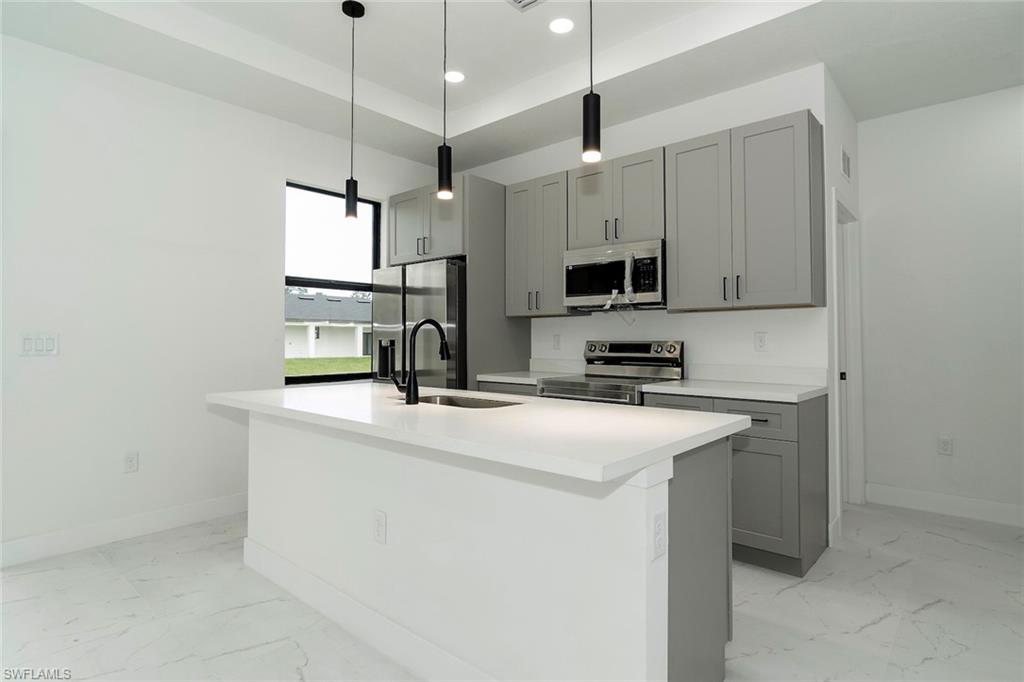 3810 29th Street Southwest Lehigh Acres, FL 33976 - Photo 10 of 48 a kitchen with kitchen island a sink stainless steel appliances and white cabinets