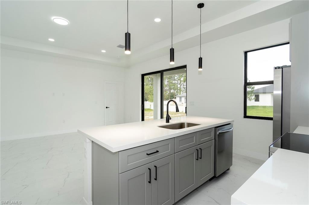 3810 29th Street Southwest Lehigh Acres, FL 33976 - Photo 12 of 48 a kitchen with a sink dishwasher and white cabinets with wooden floor