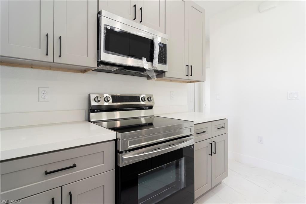 3810 29th Street Southwest Lehigh Acres, FL 33976 - Photo 13 of 48 a kitchen with stainless steel appliances white cabinets and a stove top oven