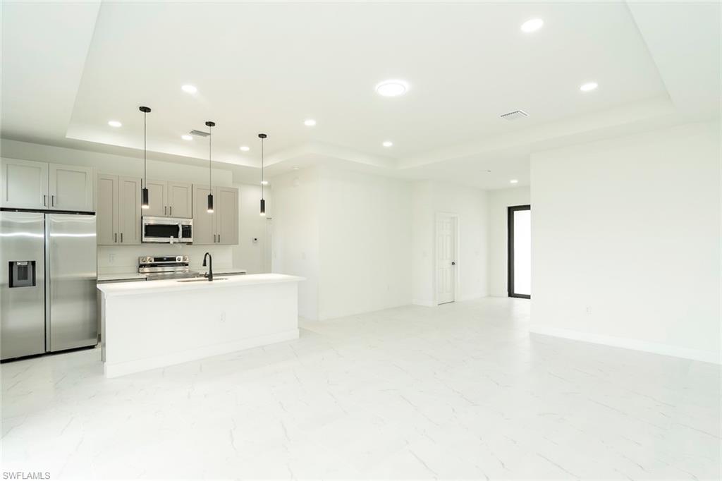 3810 29th Street Southwest Lehigh Acres, FL 33976 - Photo 4 of 48 a kitchen with kitchen island a white counter top space stainless steel appliances and cabinets