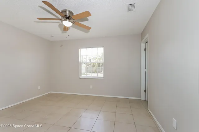 an empty room with a window and a fan