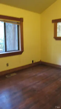 a view of an empty room with a kitchen and a window
