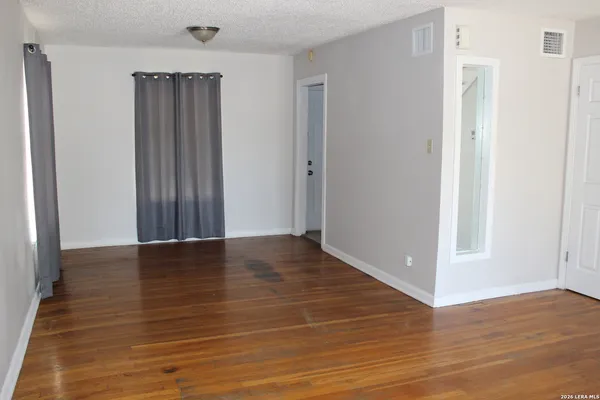a view of an empty room with wooden floor