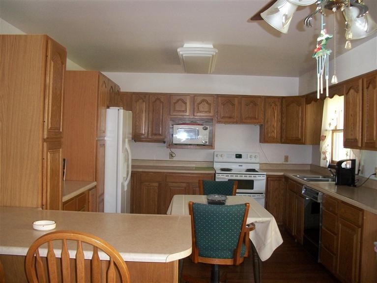 11474 Chateau Lane Demotte, IN 46310 - Photo 4 of 10 a kitchen with a table chairs refrigerator and cabinets